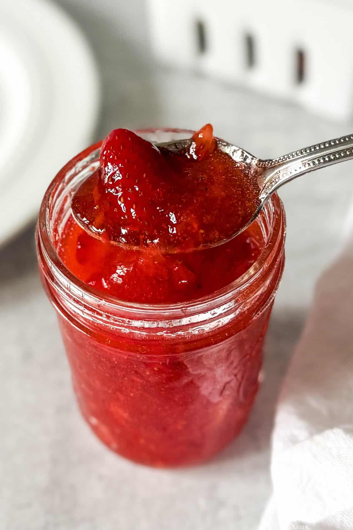 A spoonful of easy strawberry freezer jam recipe with fresh strawberries.