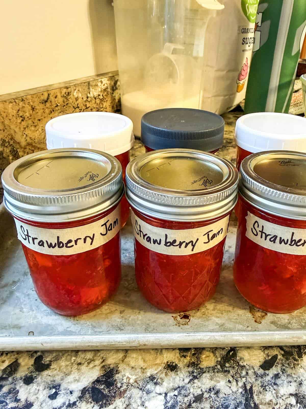 Strawberry freezer jam in mason jars labeled and ready to freeze.