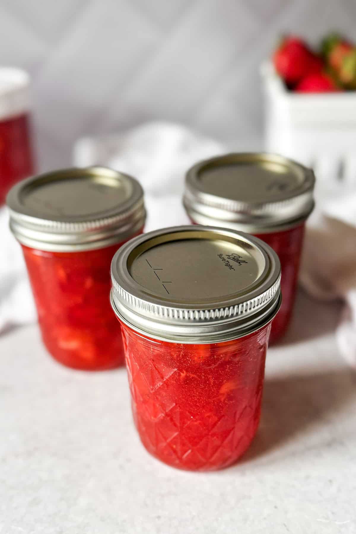 Jars of homemade strawberry freezer jam made with fresh strawberries.