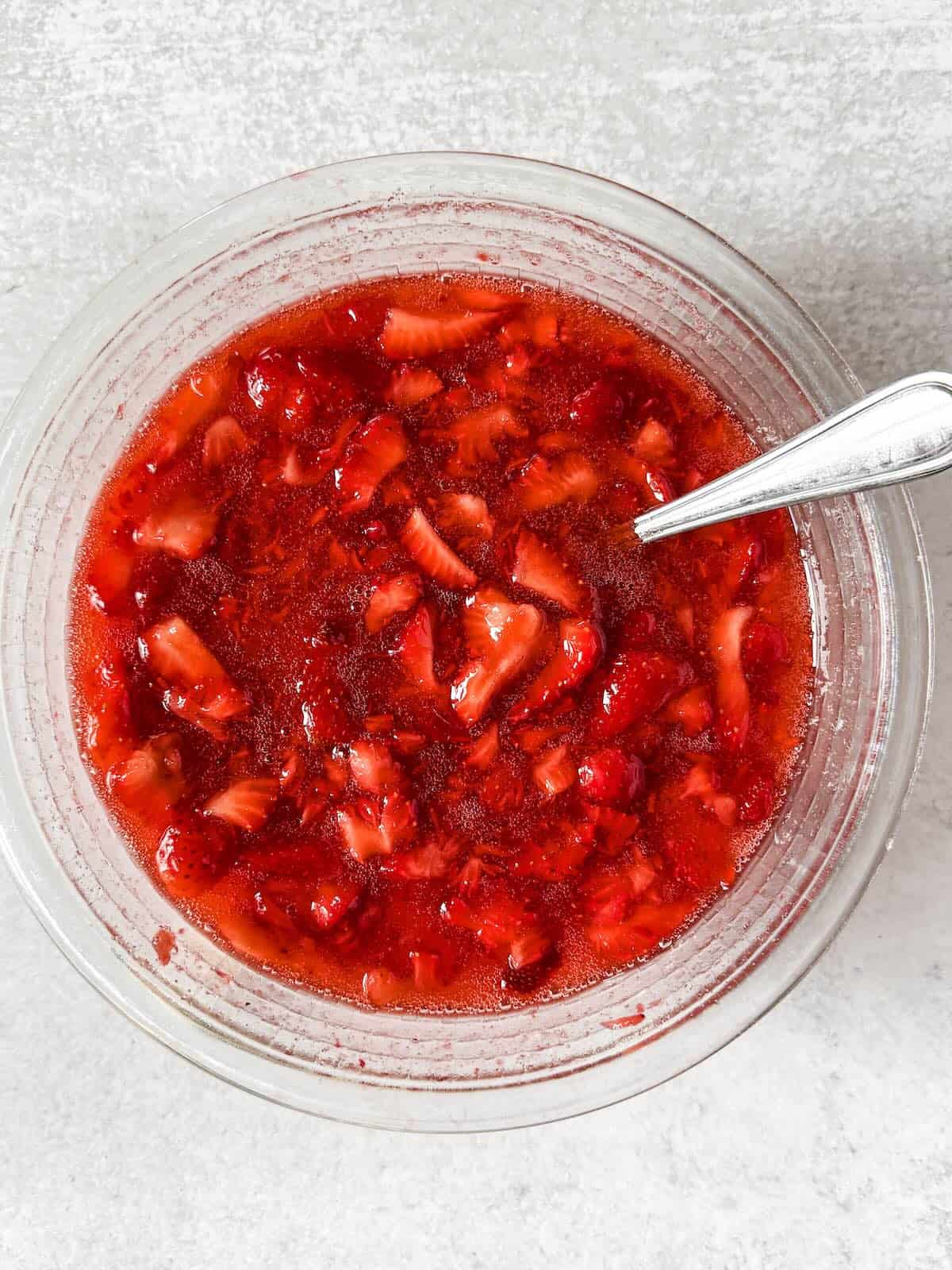 Strawberry freezer jam thickening after mixing with sugar and pectin.