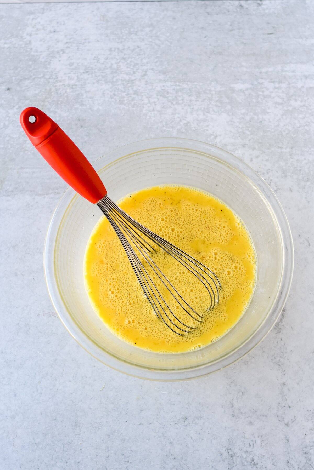 Whisked eggs and milk for crustless quiche muffins.