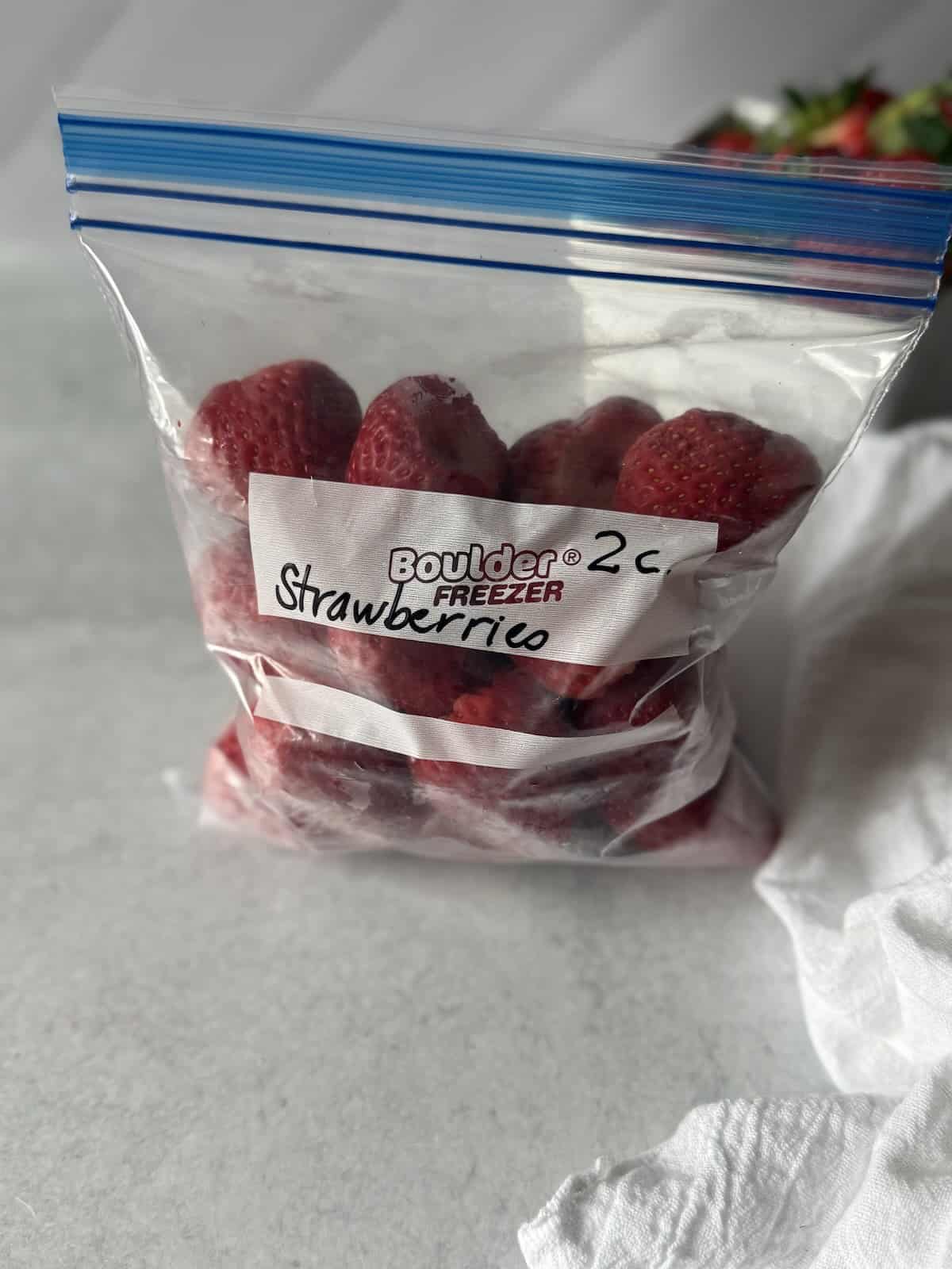 Whole frozen strawberries in a plastic zip top bag.