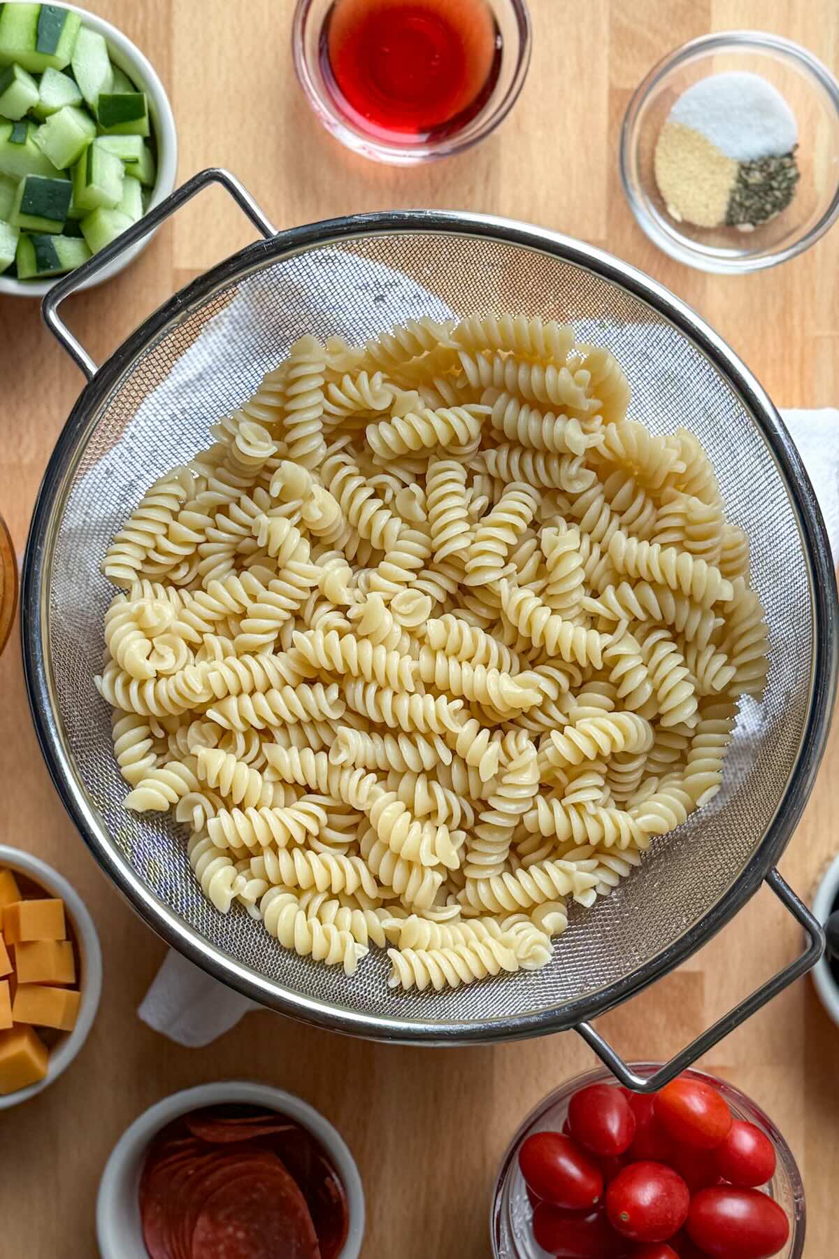 Cooked rotini pasta in a strainer after rinsing with water. 
