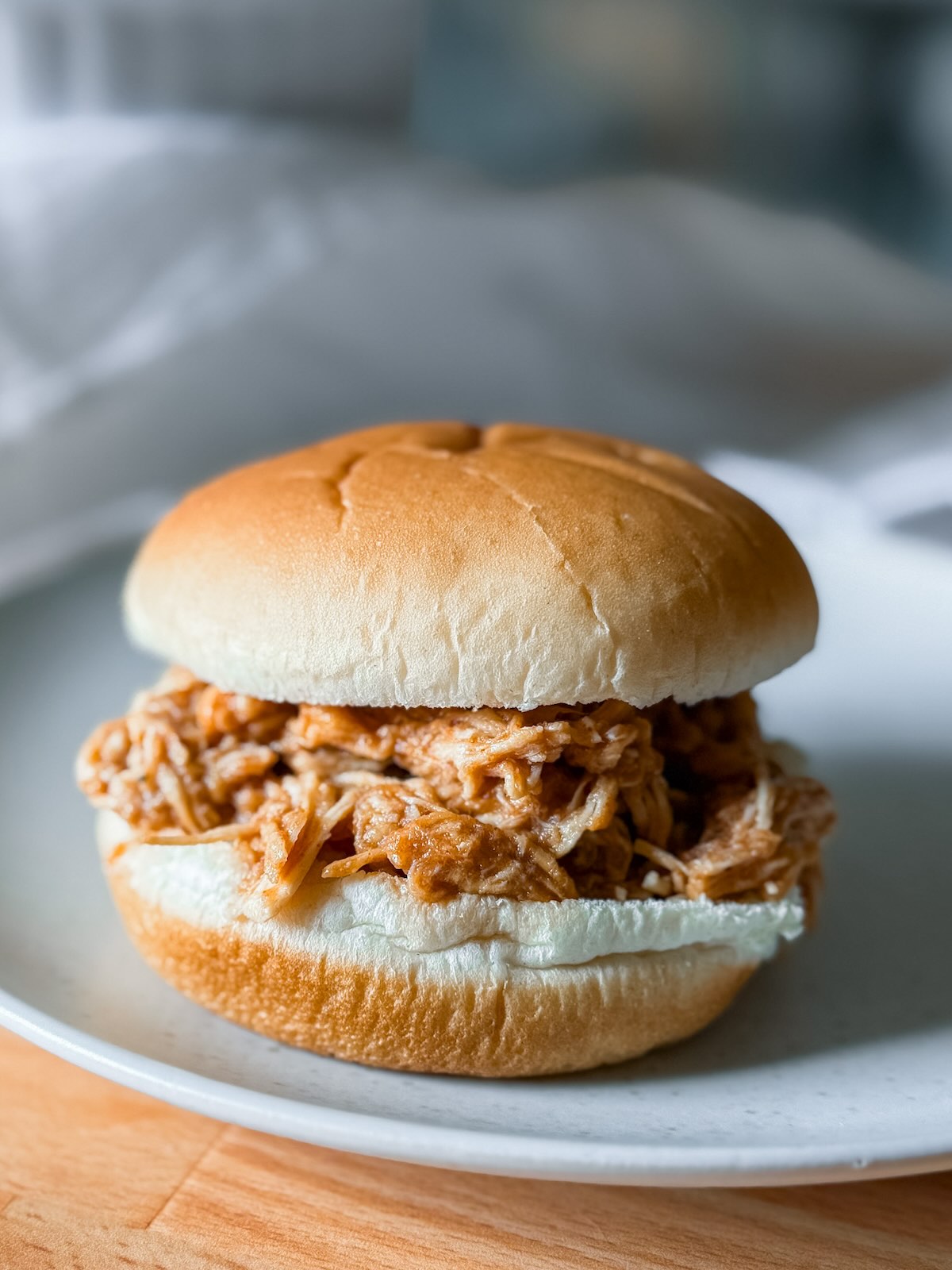 A bbq chicken sandwich plated and served on a bun.