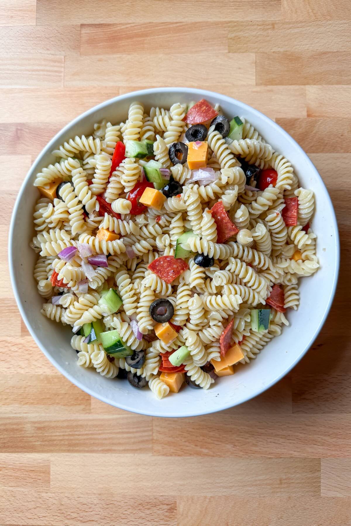 A large bowl of pasta salad with Italian dressing and vegetables for a summertime side dish.