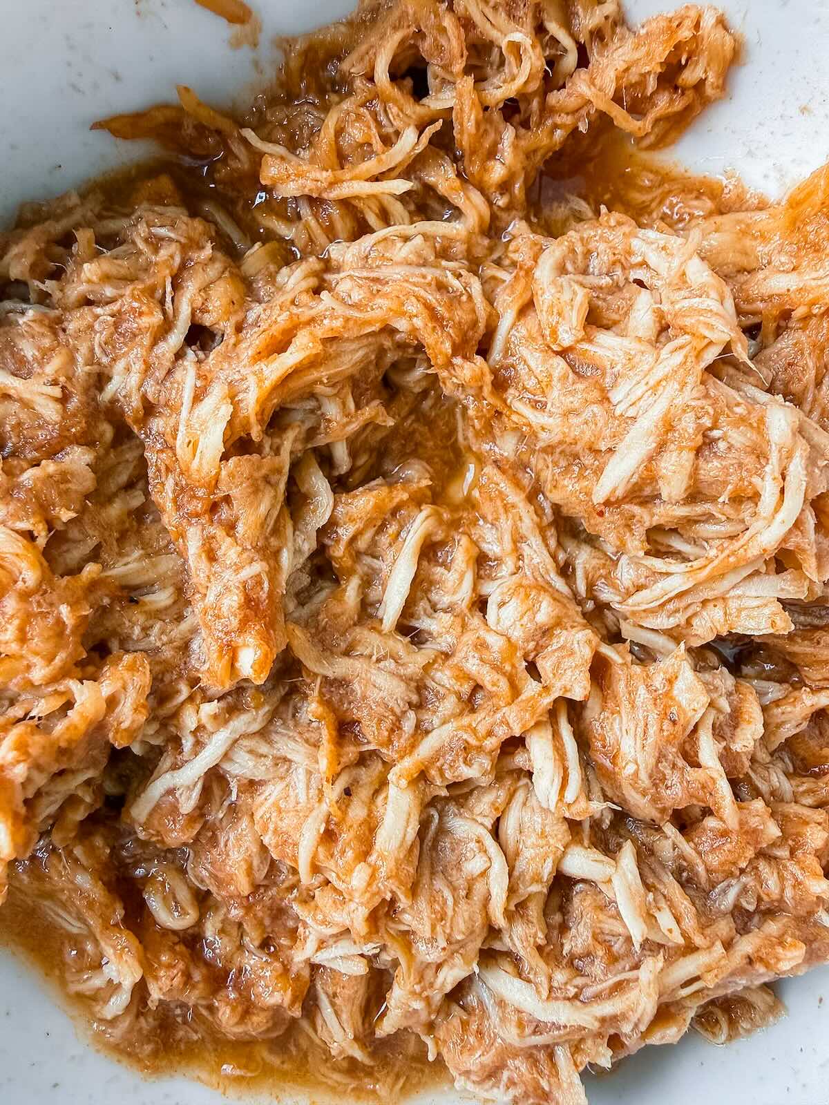 Crockpot BBQ chicken shredded and coated in sauce, ready to serve.