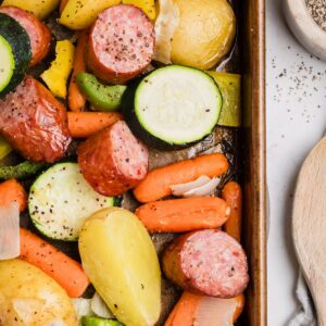 Kielbasa and vegetables roasting on a sheet pan in the oven.