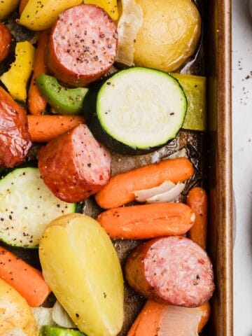Kielbasa and vegetables roasting on a sheet pan in the oven.