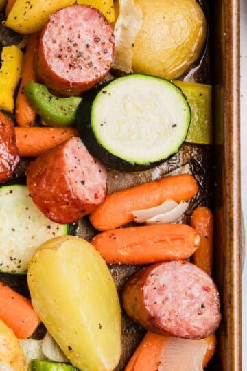 Kielbasa and vegetables roasting on a sheet pan in the oven.