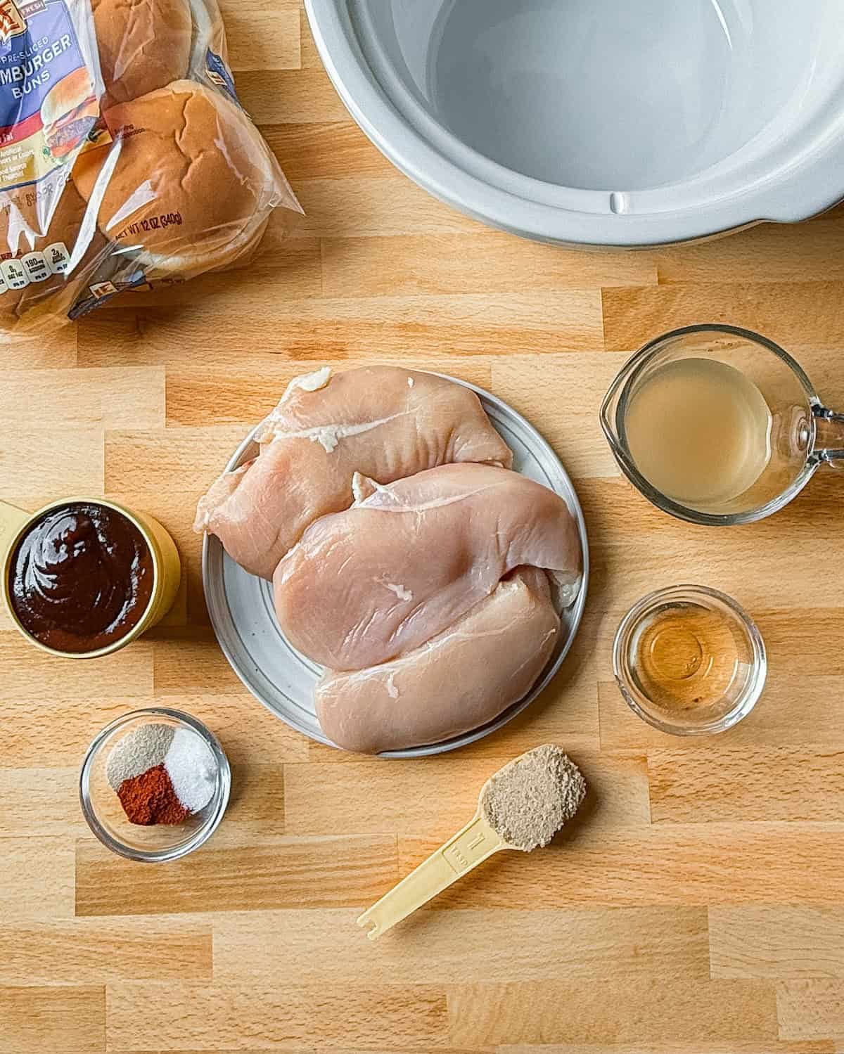 Ingredients to make slow cooker chicken with bbq sauce, spices, vinegar and brown sugar.