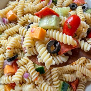 Easy Italian pasta salad made with rotini, vegetables, cheese, and Italian dressing in a large serving bowl.