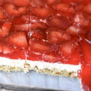 A layered strawberry pretzel salad cut and ready to serve.