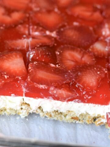 A layered strawberry pretzel salad cut and ready to serve.