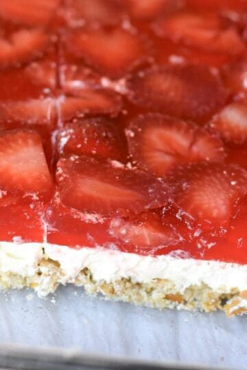 A layered strawberry pretzel salad cut and ready to serve.