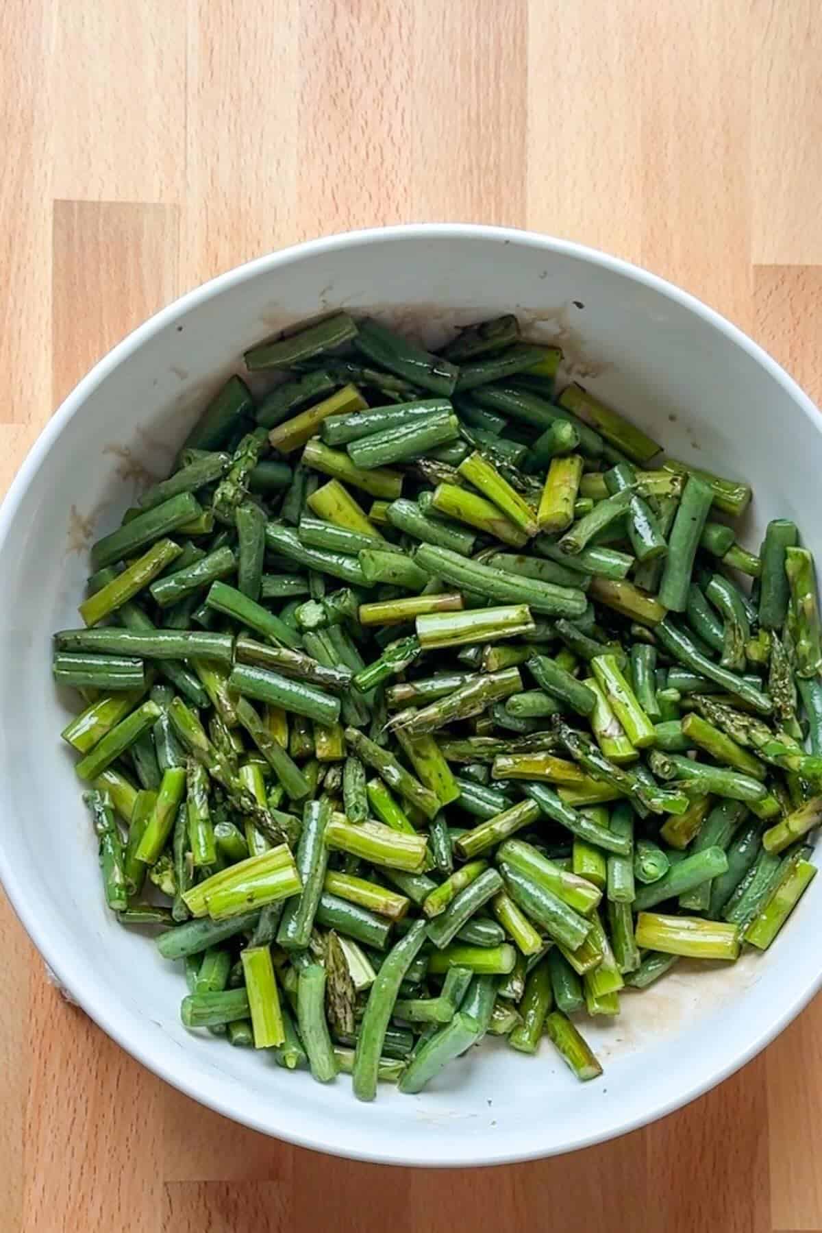 A serving bowl with roasted green beans and asparagus.