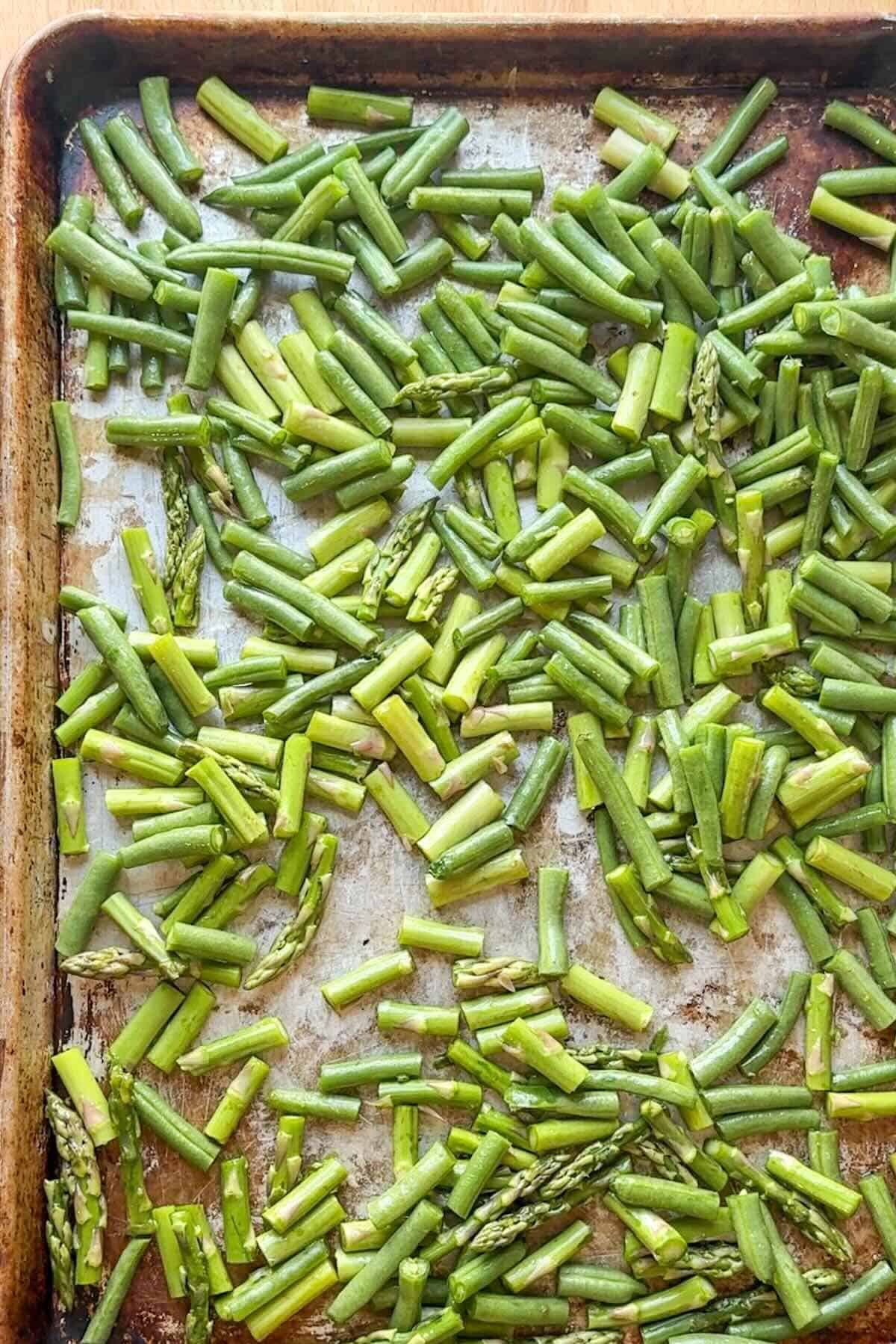 Asparagus and green beans before roasting on a sheet pan with olive oil and seasoning.