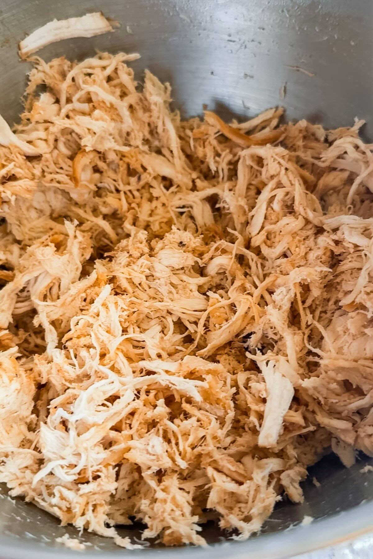 A batch of chicken breast shredded in a mixer bowl.