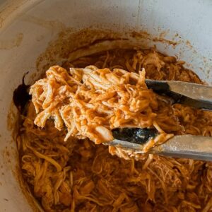 A close up of shredded chicken with bbq sauce made in the crockpot.