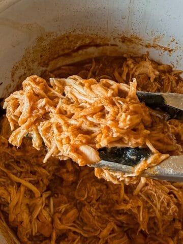 A close up of shredded chicken with bbq sauce made in the crockpot.