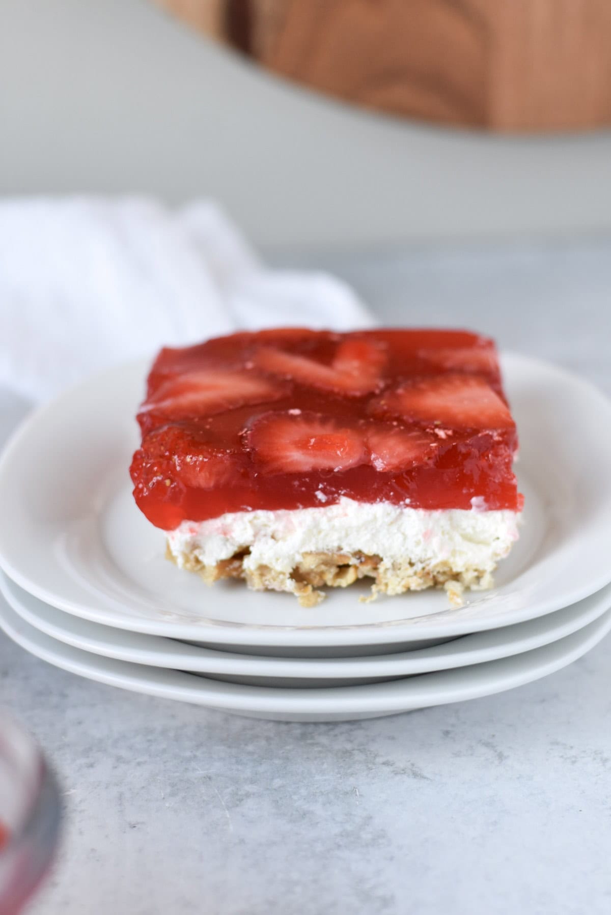 Slice of strawberry pretzel salad showing layers of crunchy pretzel crust, creamy filling, and strawberry gelatin.