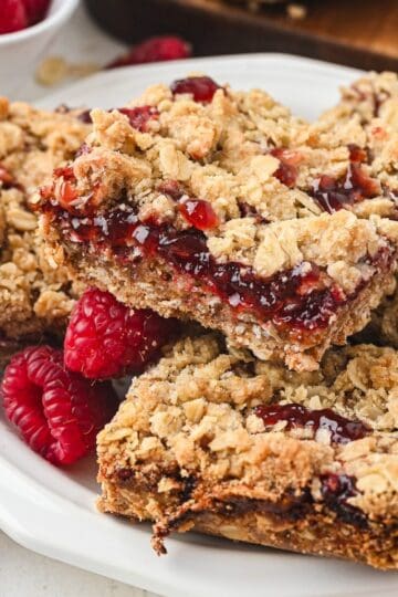 Stacked raspberry jam dessert bars on a white plate.