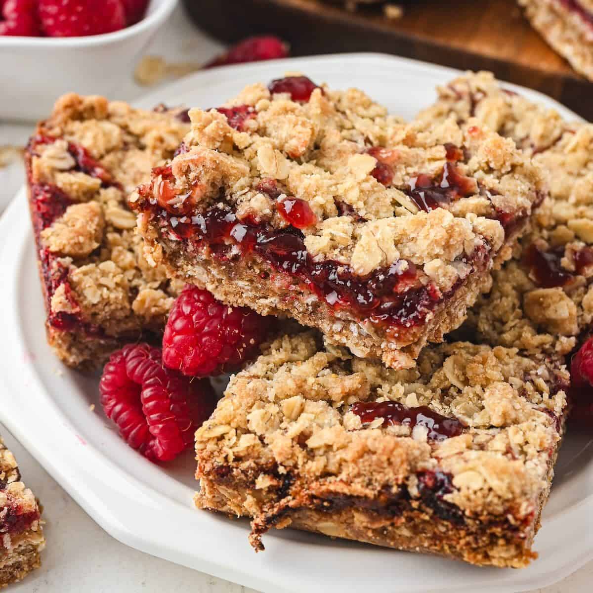 Stacked raspberry jam dessert bars on a white plate.