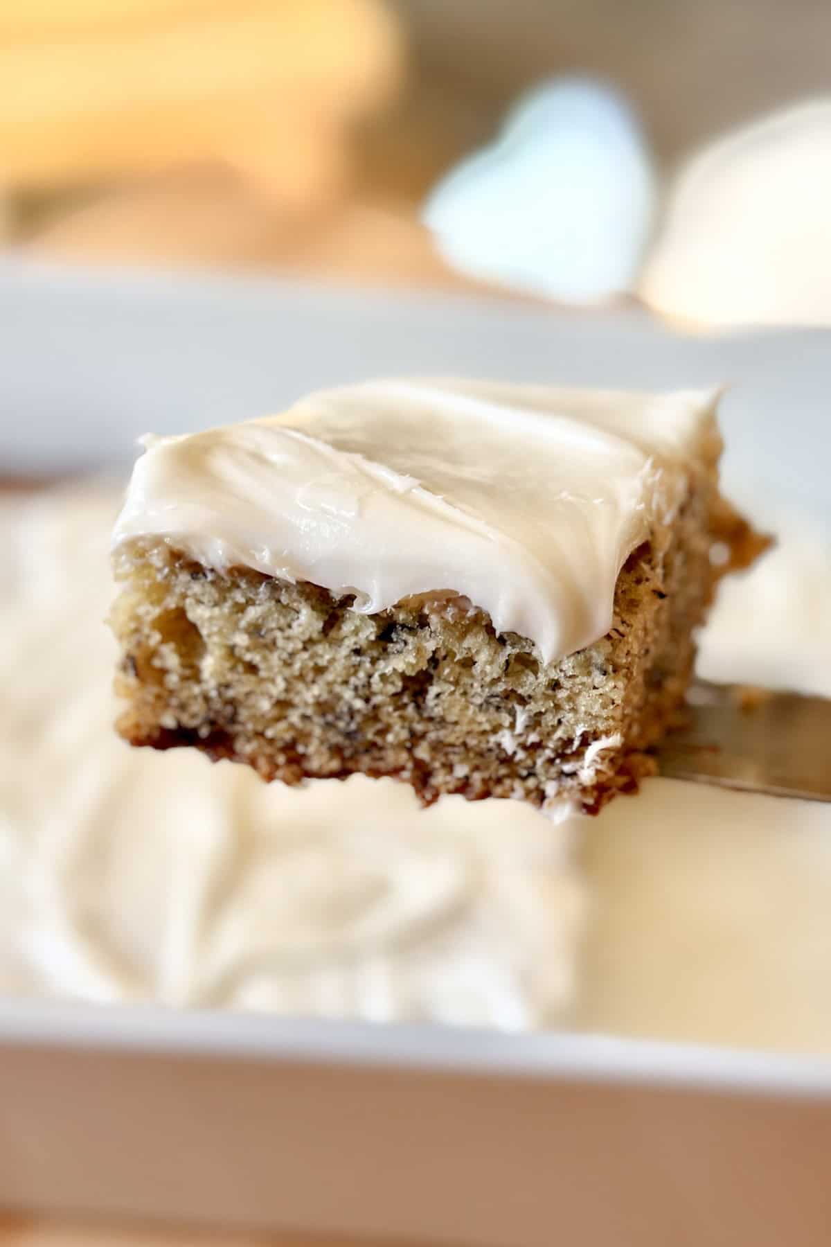 Close up of a moist banana bar topped with cream cheese frosting.