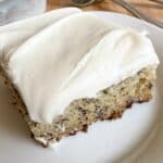 Banana bars with cream cheese frosting sliced into squares on a serving plate.