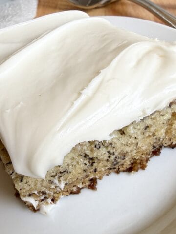 Banana bars with cream cheese frosting sliced into squares on a serving plate.