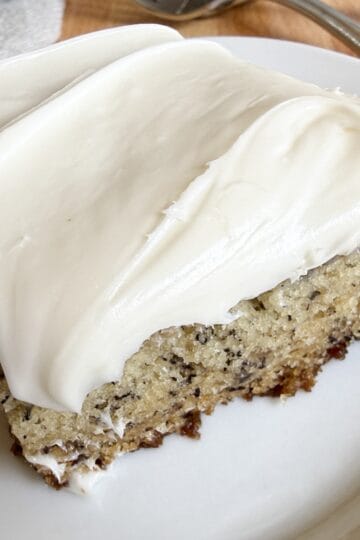 Banana bars with cream cheese frosting sliced into squares on a serving plate.