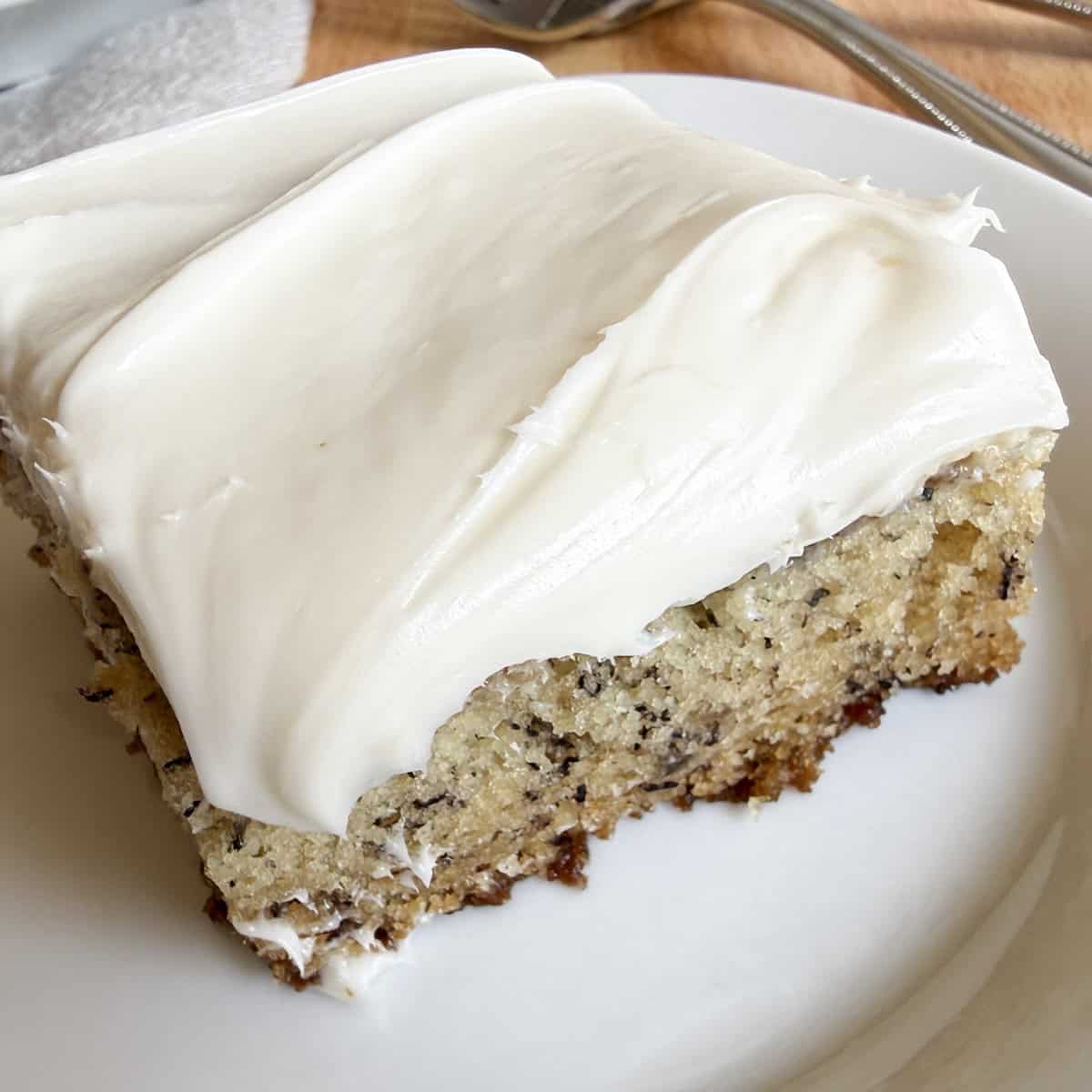 Banana bars with cream cheese frosting sliced into squares on a serving plate.