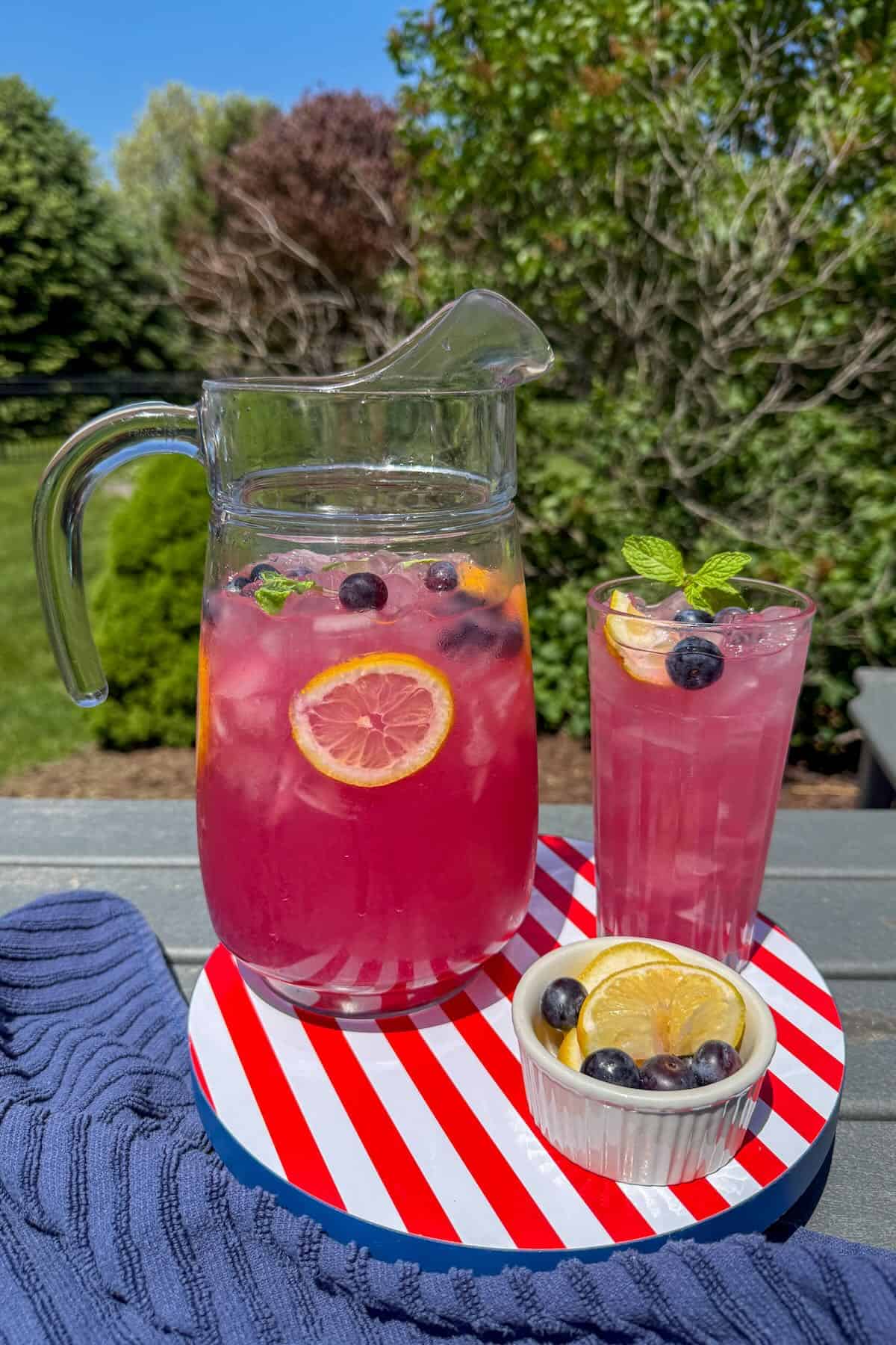 A red, white and blue try with a glass pitcher of blueberry lemonade on the patio.