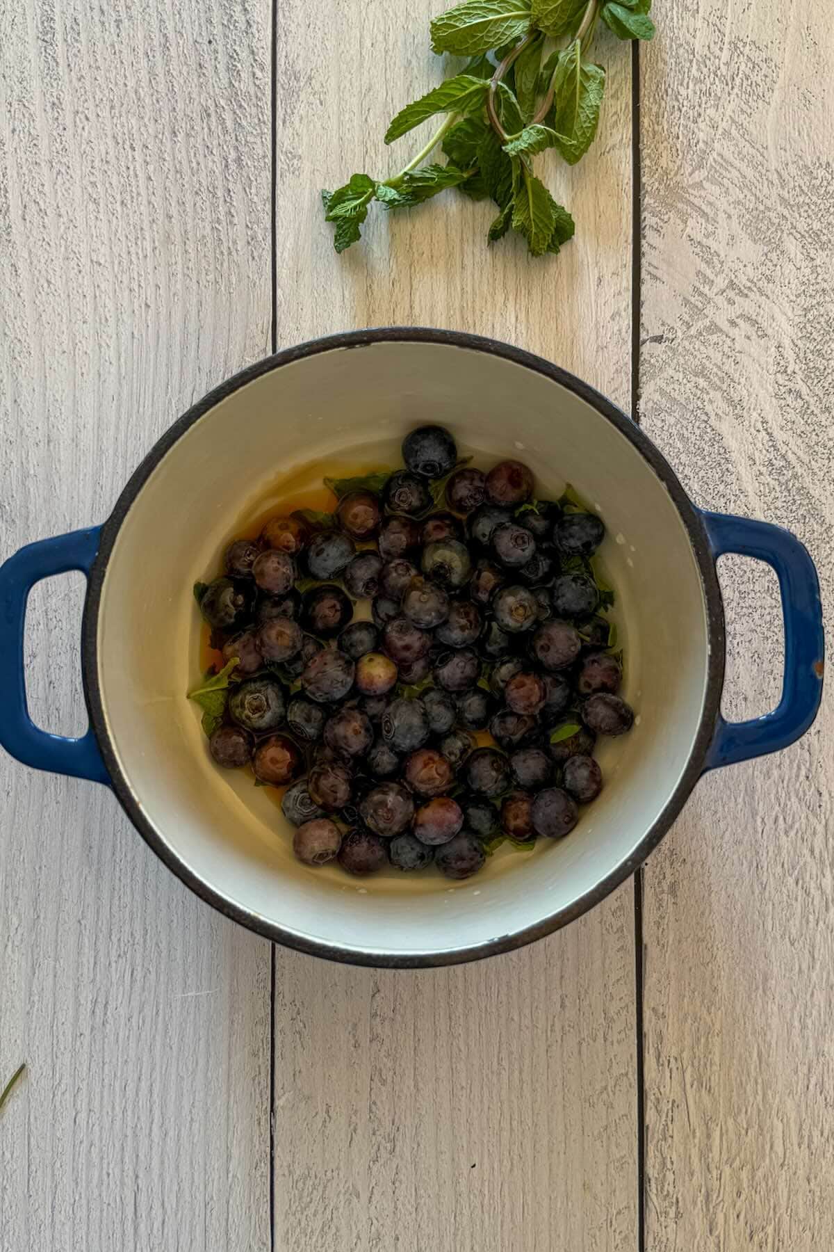 Blueberries, honey, water and crushed mint in a pan before simmering.