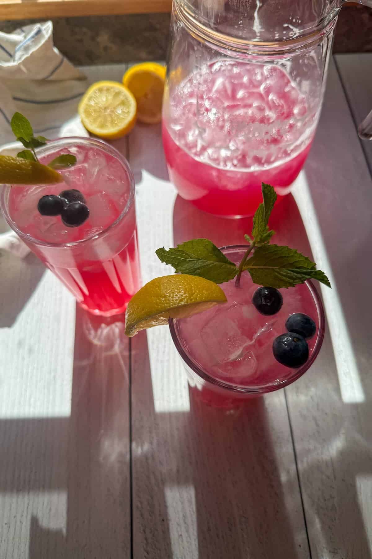 An overhead shot of glasses filled with ice and lemonade garnished with blueberries.