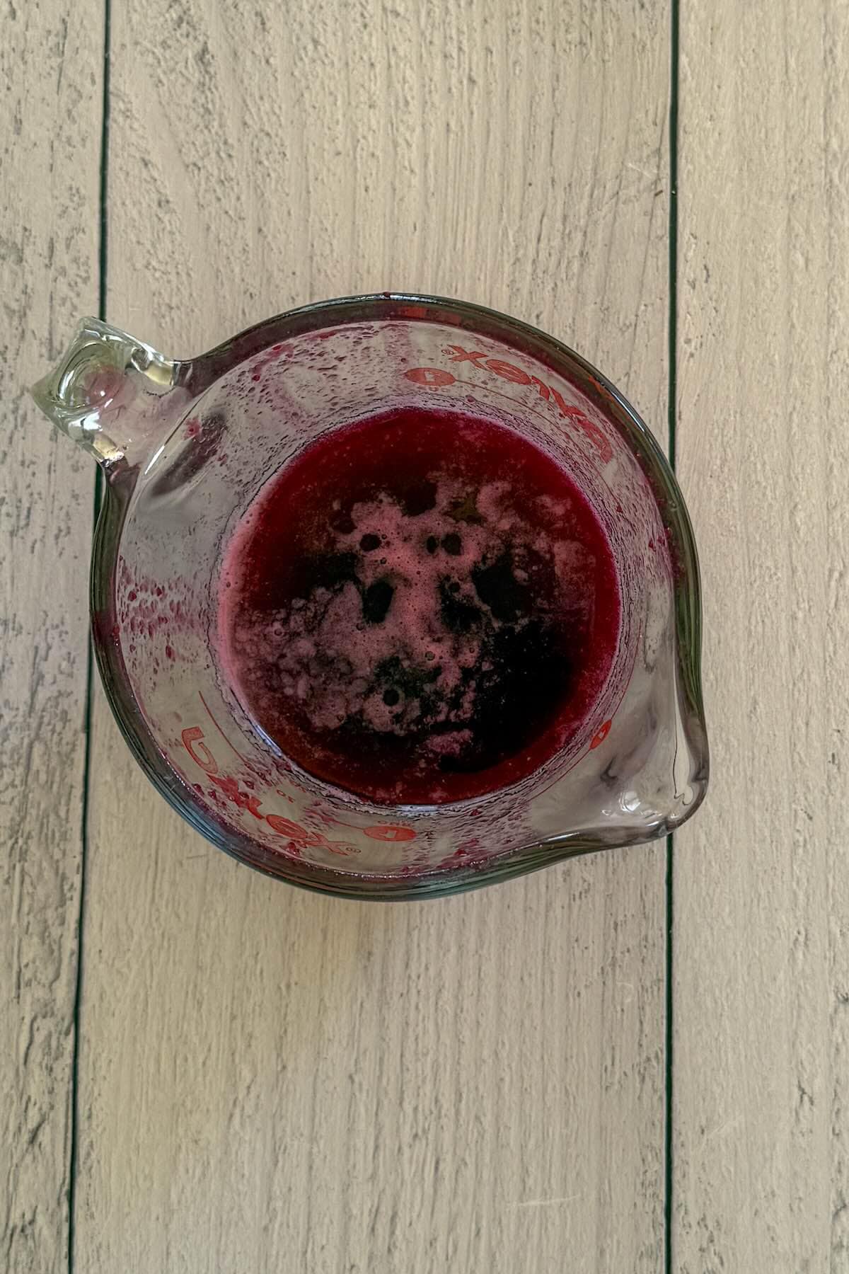 A measuring cup with blueberry simple syrup to cool.