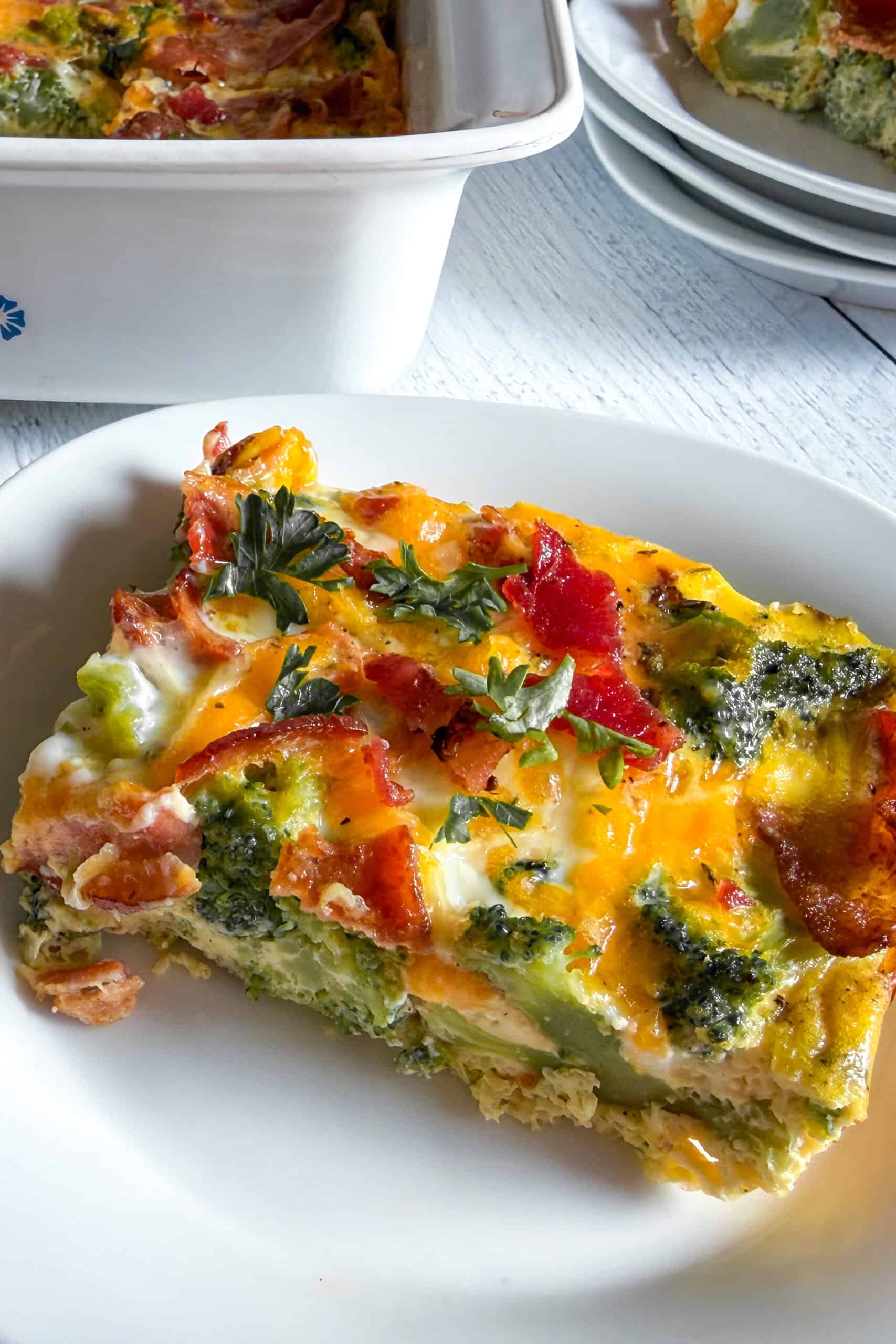 Close-up slice of low carb bacon broccoli breakfast casserole showing fluffy eggs, broccoli, bacon, and cheddar cheese.