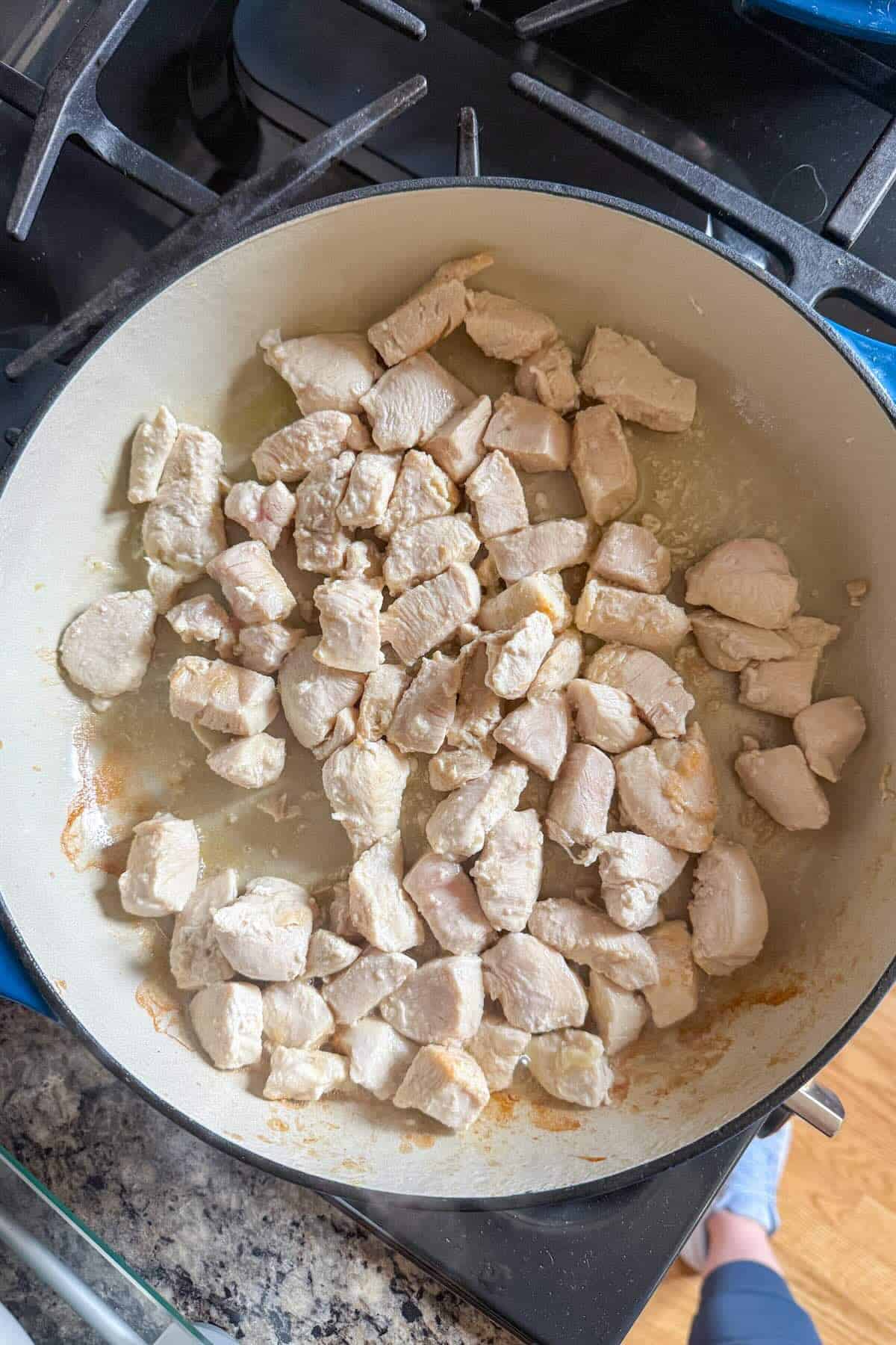 Cubed chicken cooked in a skillet as a base for stir fry.