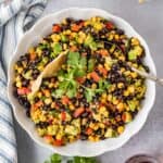 Cowboy caviar dip with black beans, corn, avocado, and tortilla chips in a serving bowl.