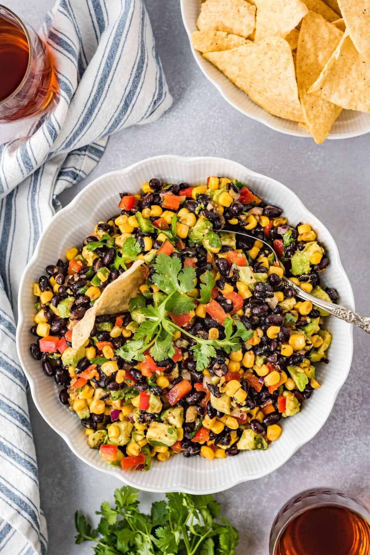 Cowboy caviar dip with black beans, corn, avocado, and tortilla chips in a serving bowl.