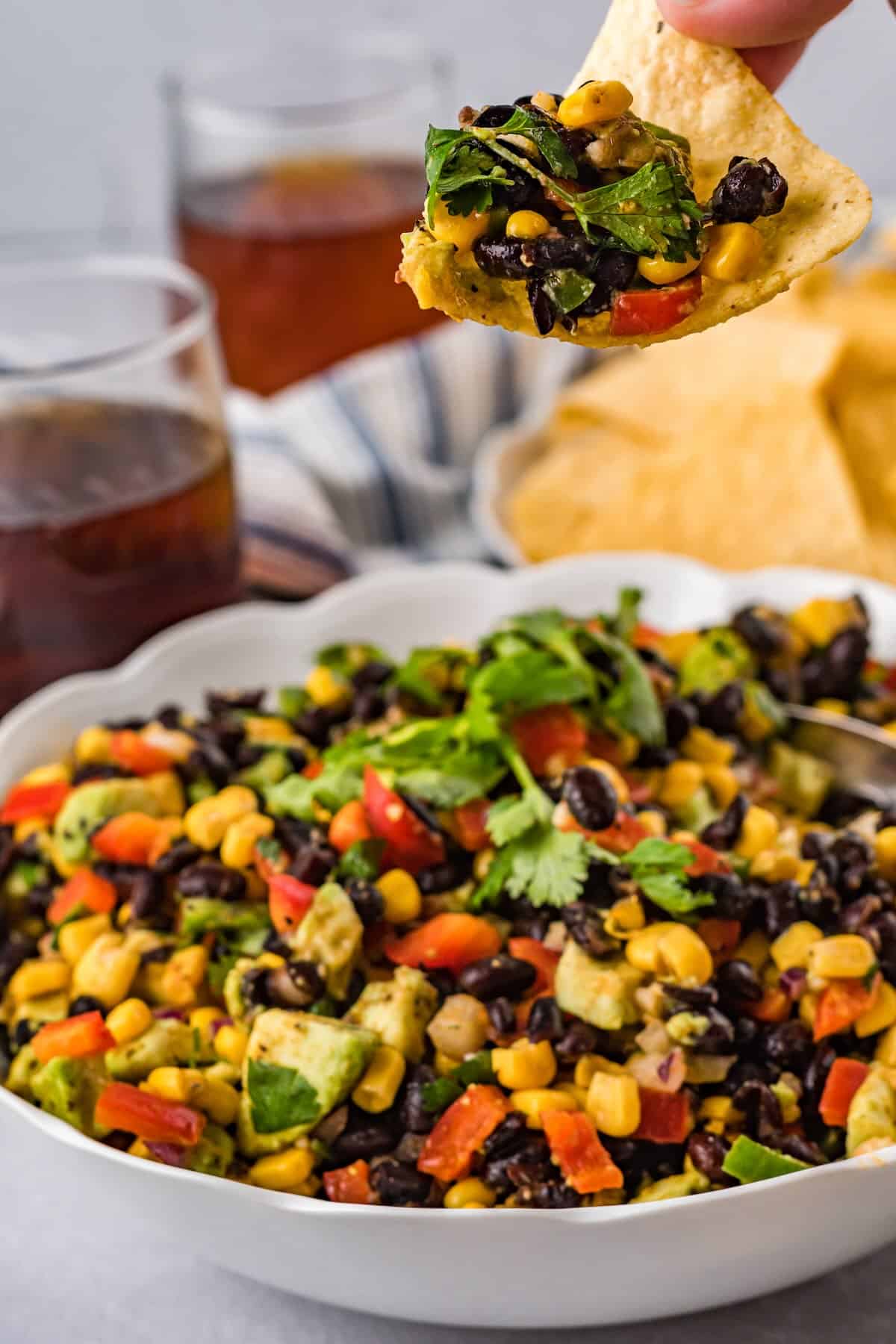 Tortilla chip scooping cowboy caviar with beans, corn, peppers, and avocado.