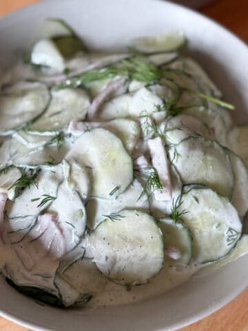 Creamy cucumber salad with sour cream and fresh dill in a serving bowl.