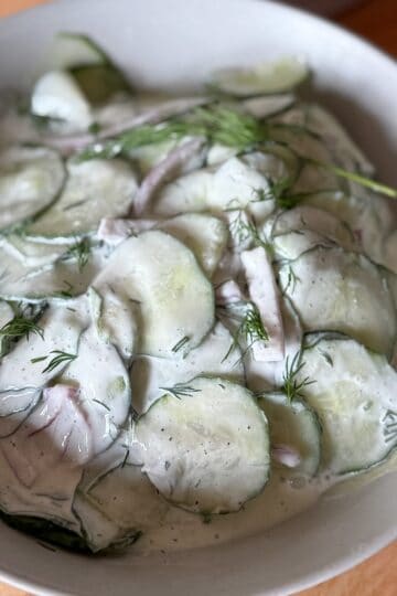 Creamy cucumber salad with sour cream and fresh dill in a serving bowl.