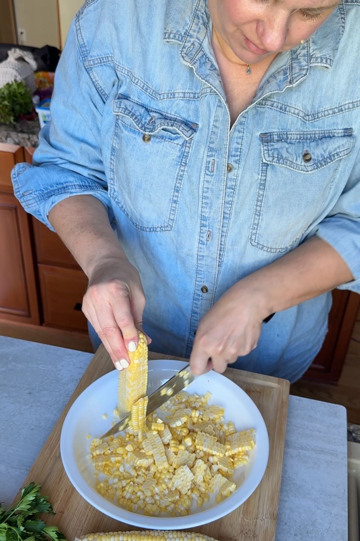 Cutting sweet corn off the cob into a pie plate.