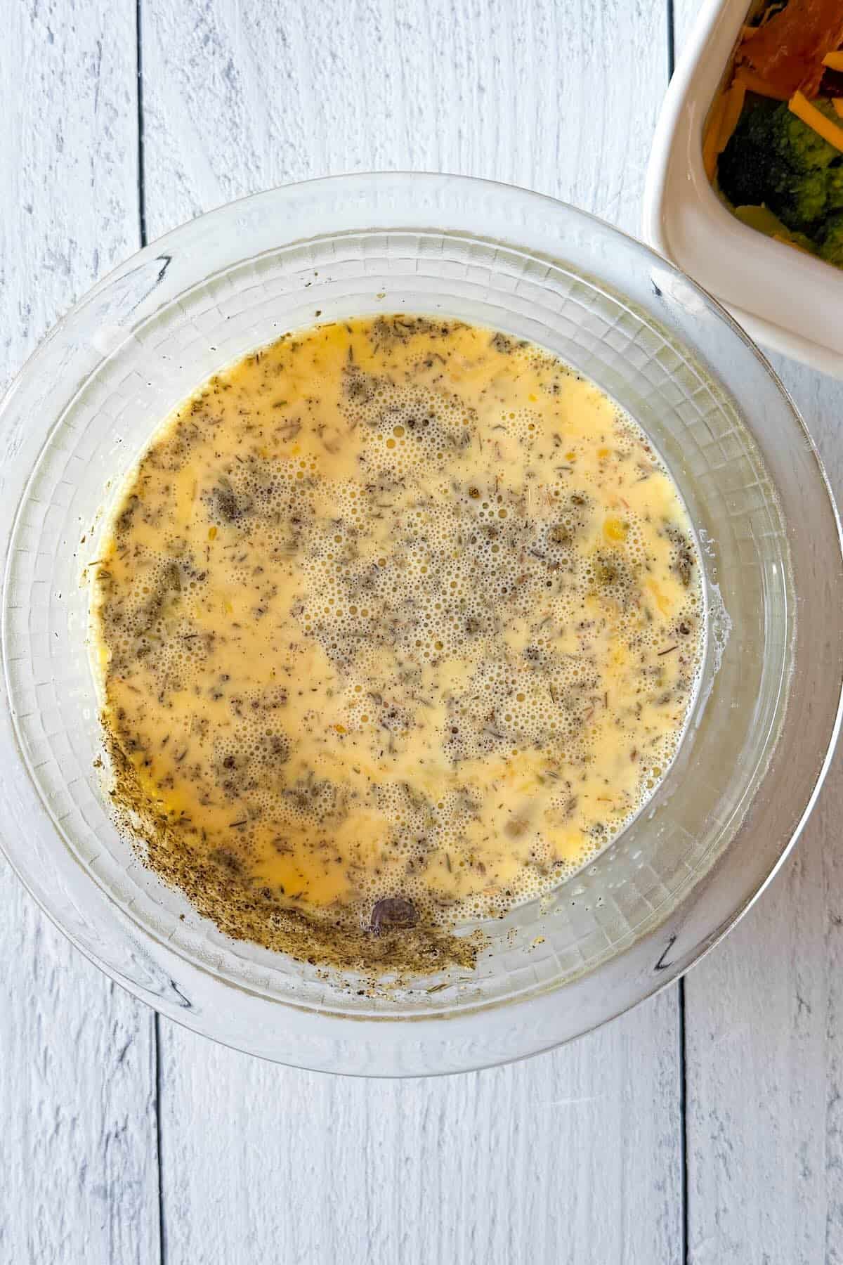 Egg and cream mixture whisked together with seasonings for low carb breakfast casserole.
