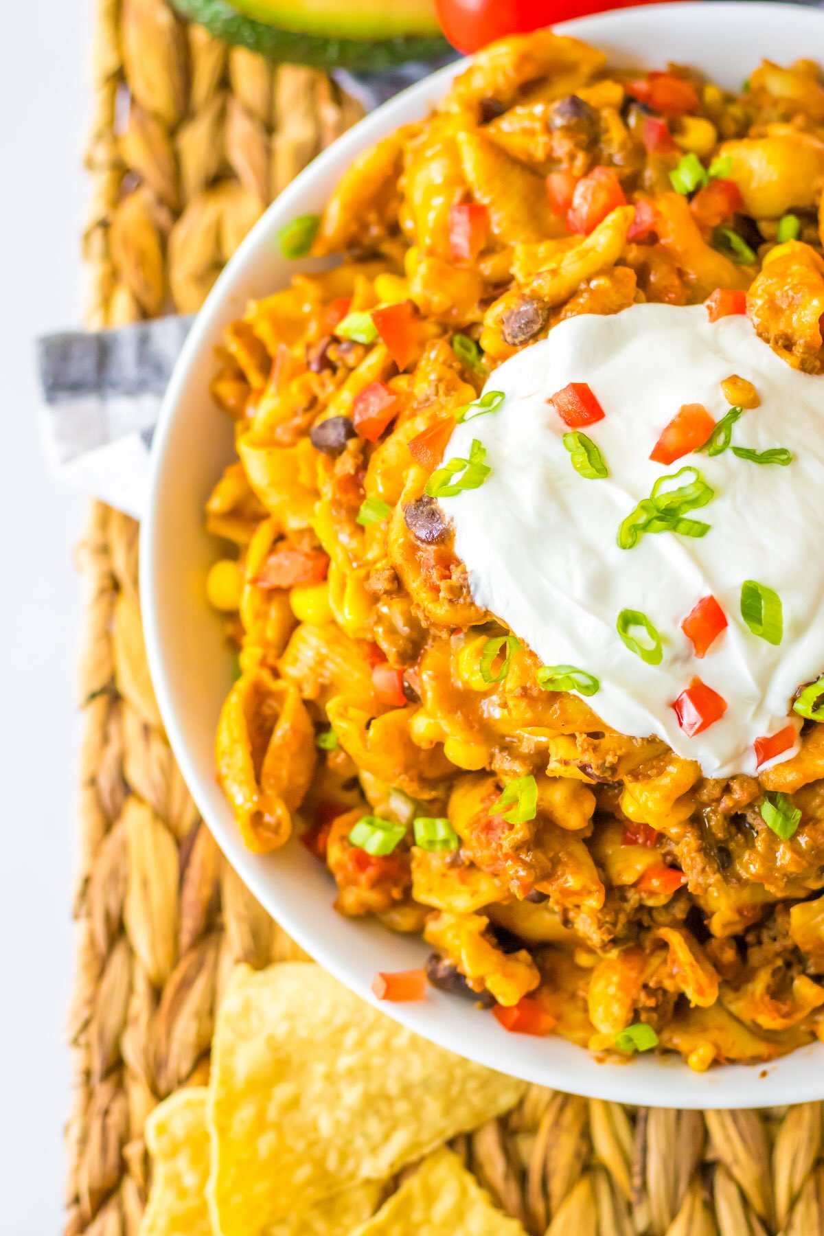 Slow cooker taco pasta topped with sour cream, tomatoes, shredded cheese, and green onions.