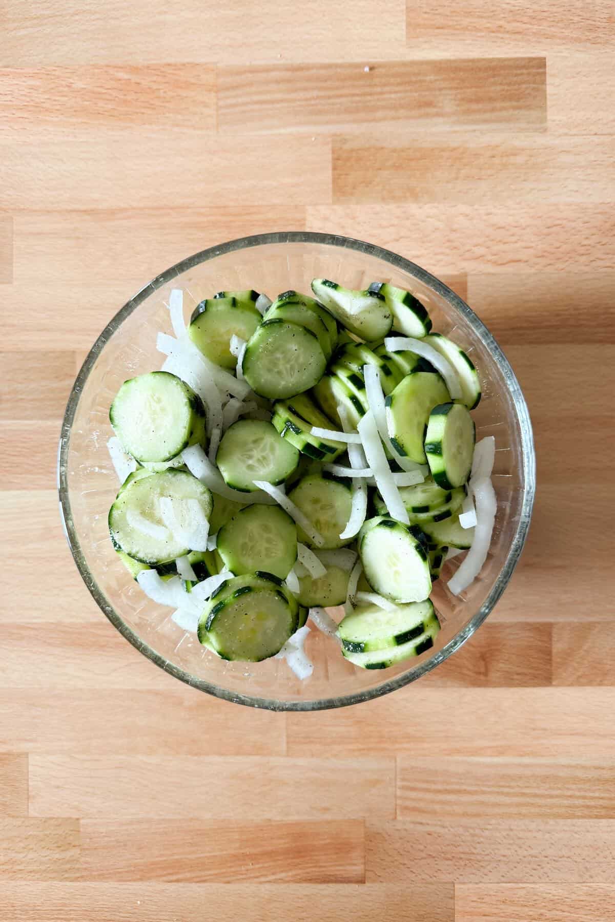 Tossed cucumbers and onions in marinade to coat evenly before chilling.