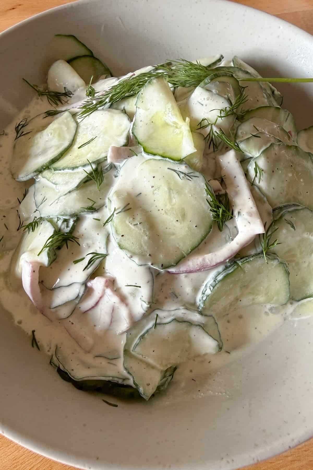 Tossing cucumbers and onions in creamy sour cream dressing.