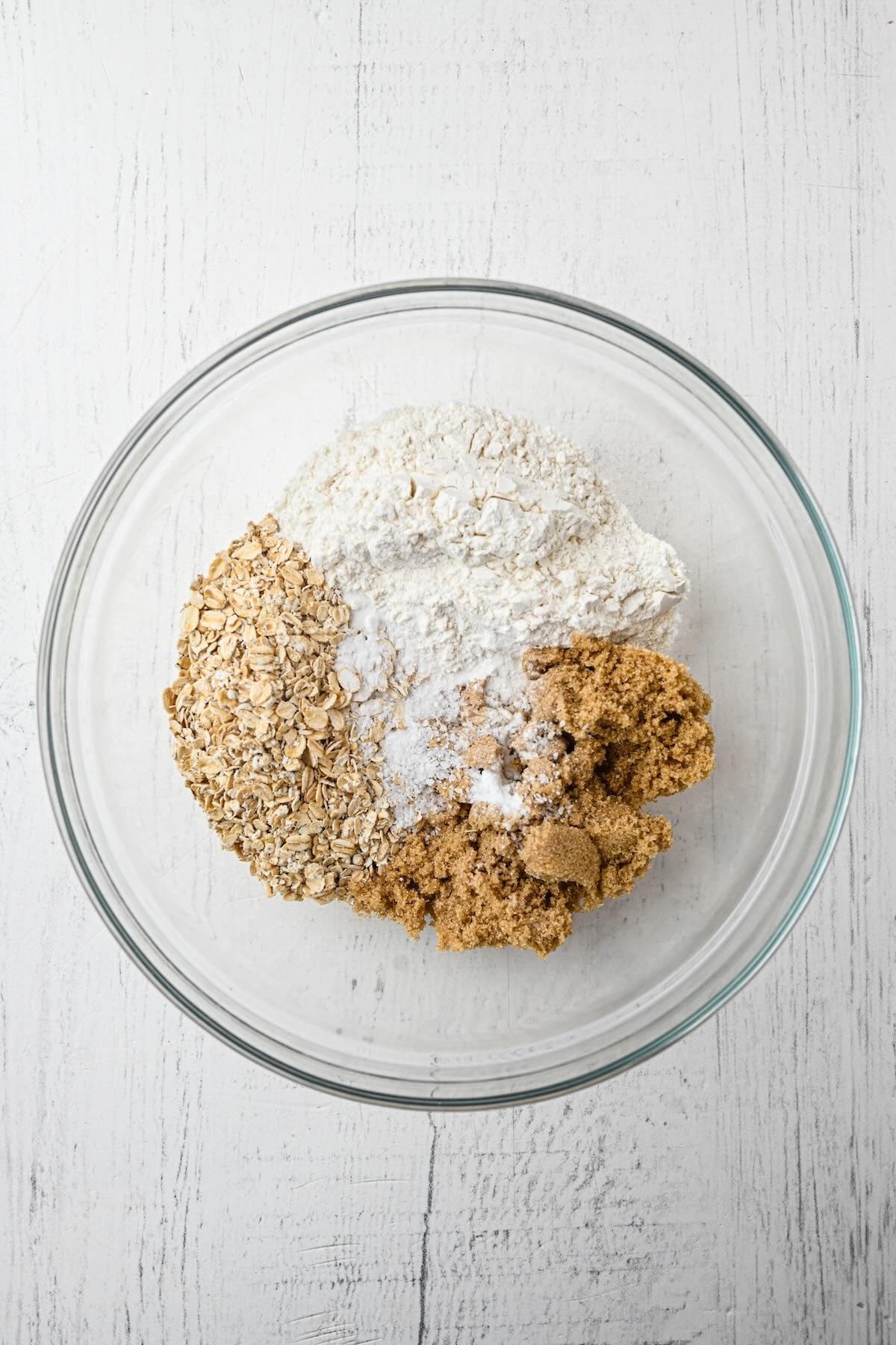 Rolled oats, flour, brown sugar, baking soda, and salt mixed together in a bowl.