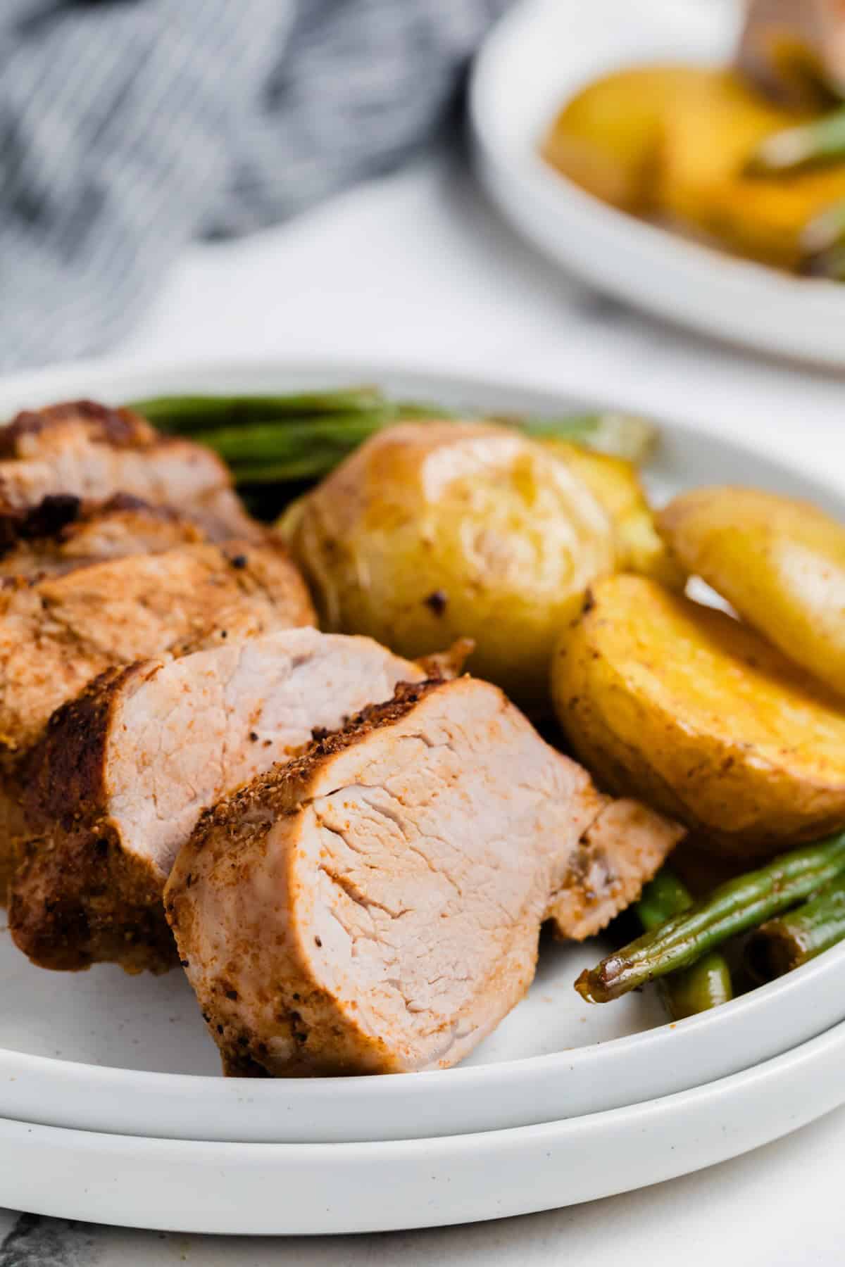 A juicy pork tenderloin cooked in one pan alongside potatoes and green geans.