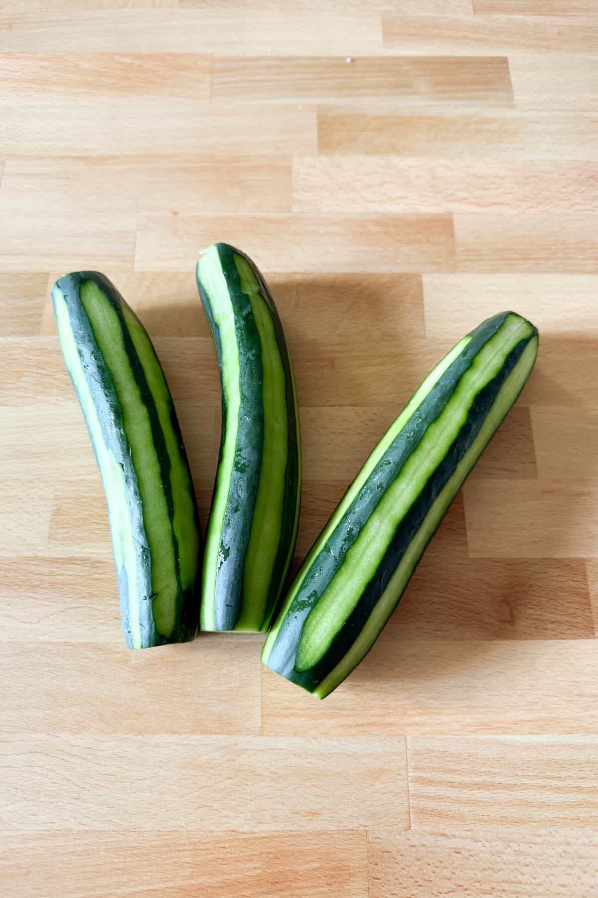 Partially peeled cucumbers with the ends trimmed off.